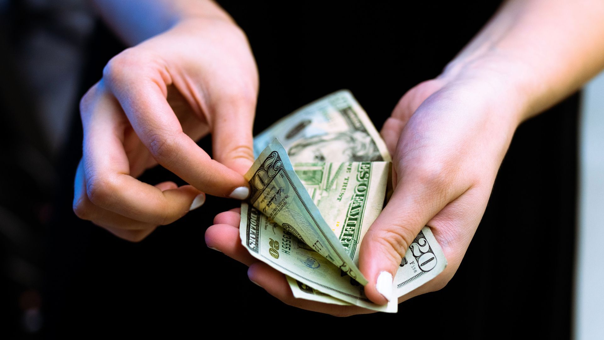 A view of hands holding and counting U.S. dollar bills