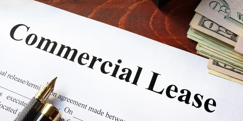 Commercial lease agreement document with pen and stack of cash on a wooden desk