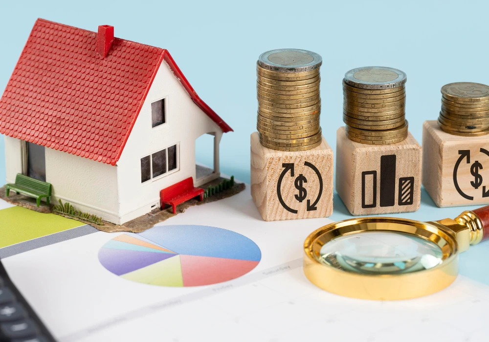Miniature house, stacked coins on wooden blocks with finance icons, pie chart, and magnifying glass