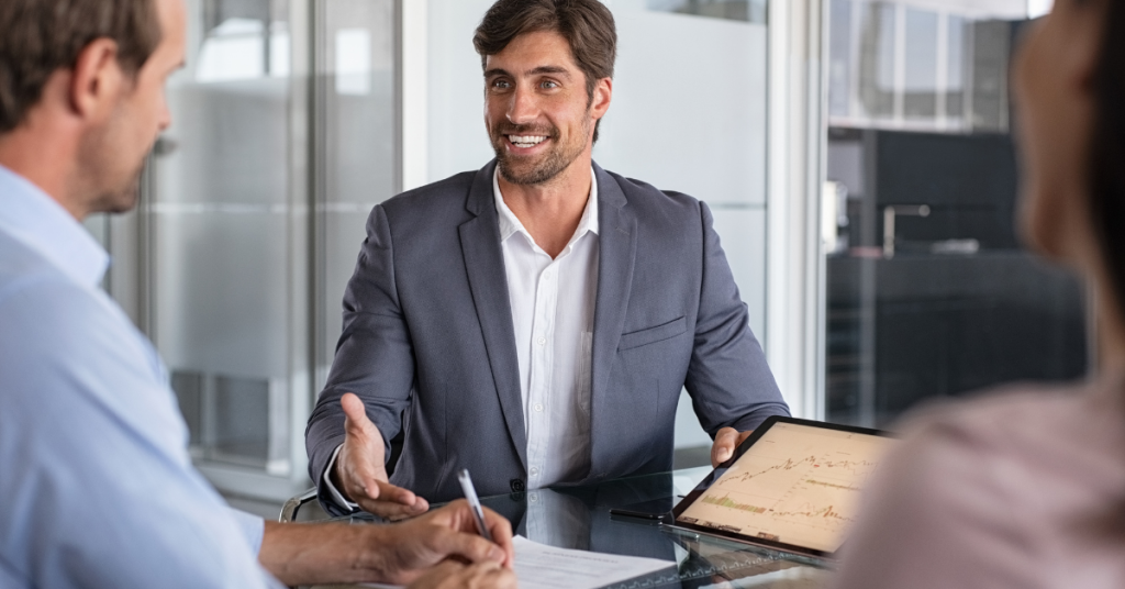 Smiling financial advisor presenting investment insights to clients using a tablet during a meeting. Smiling financial advisor presenting investment insights to clients using a tablet during a meeting