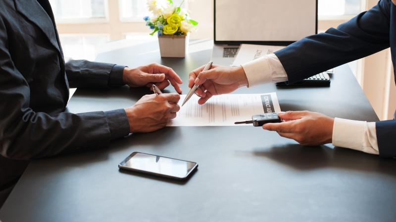 close up of two hands signing a lease agreement paper