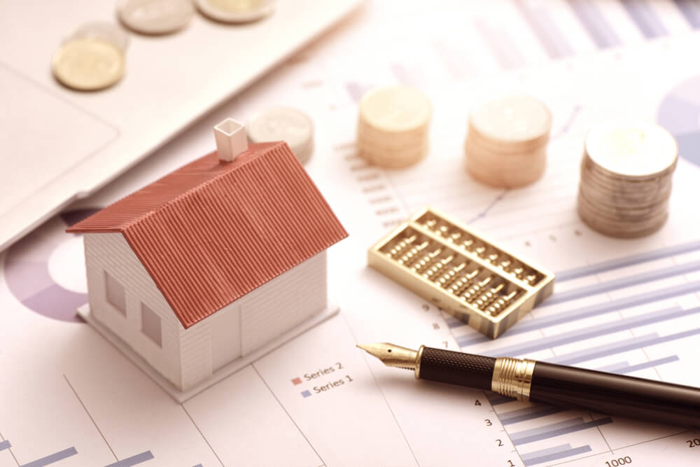 miniature house, and a pen placed on charts