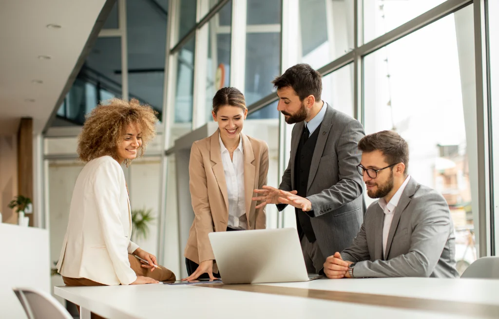 Group of professionals collaborating around a laptop in a modern office, discussing technology or risk management strategy