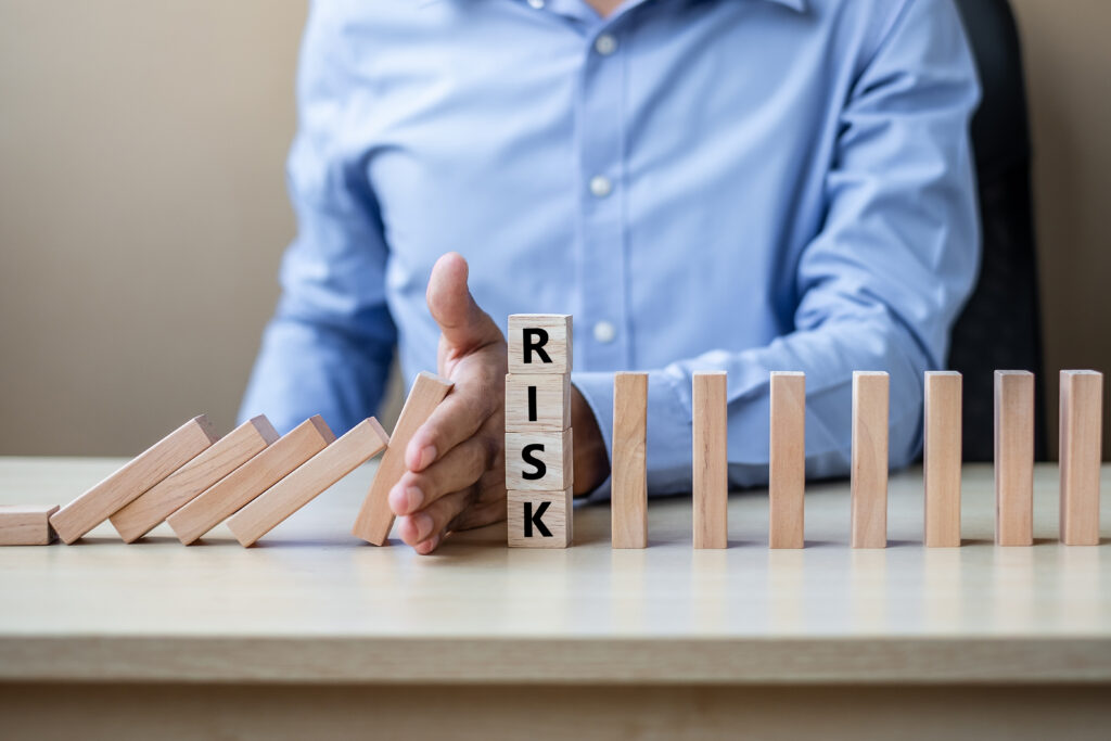 Hand stops dominoes with RISK block.
