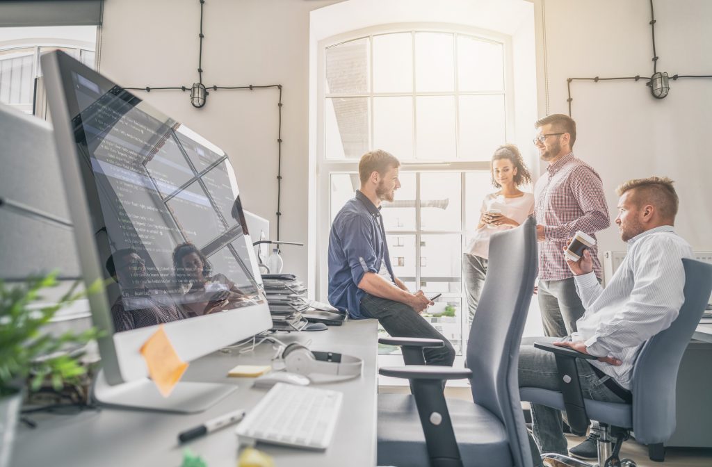 Team meeting in a modern tech office with code on screen